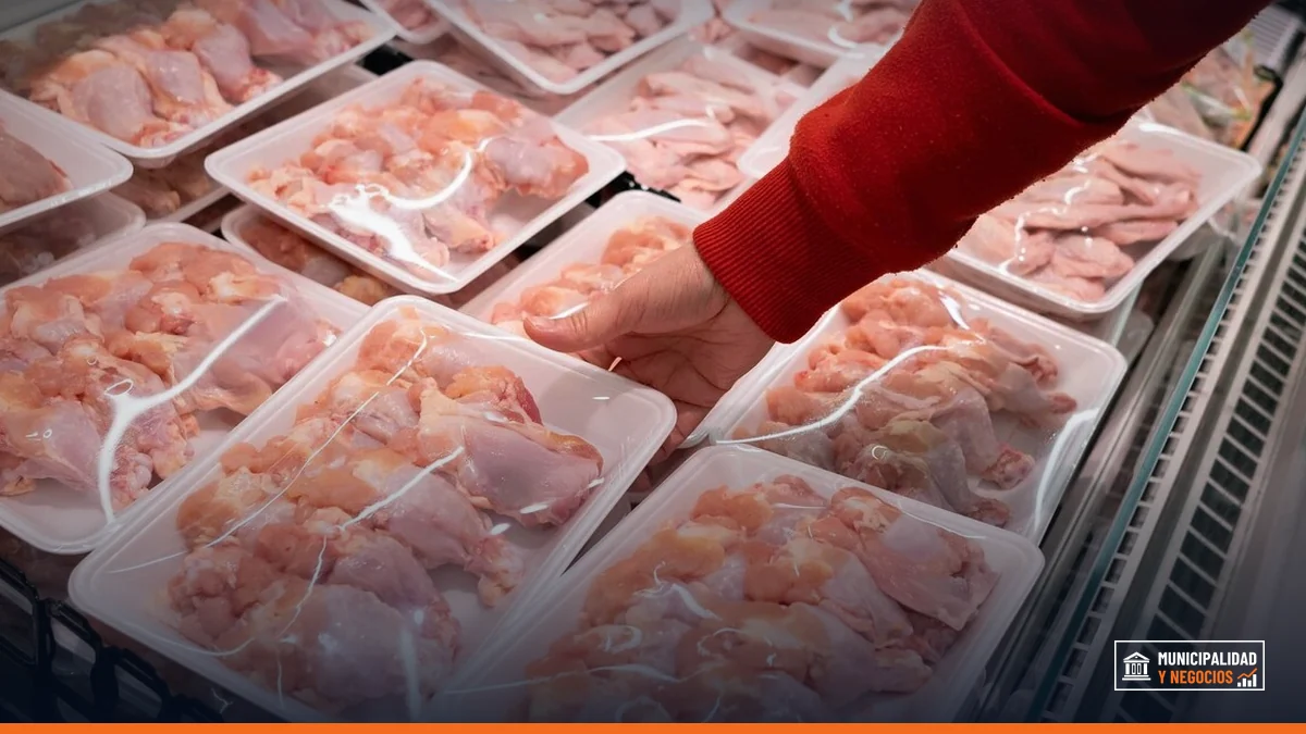 Camareros en un supermercado distribuyen pollo fresco en cajas de venta.
